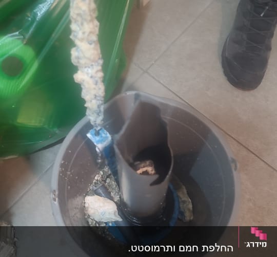 חלקי דוד שמש עם אבנית בתוך דלי על הרצפה